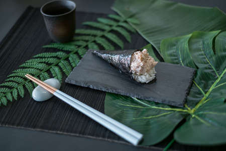 Temaki Tuna Sushi on restaurant table served on black tray with chopsticks. Palm branches on the background. tuna Temaki Hand Roll. Menu, advertisingの写真素材