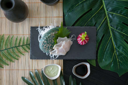 Decorated sashimi with sauce and reddish on black tray in Japanese restaurant. Flat lay with palm branches. Japanese traditional food. for the menu.の写真素材