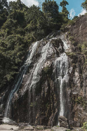 Picturesque waterfall in the mountains. Beautiful view of a high waterfall in the forest in Laos. The extraordinary nature of Asia.の写真素材