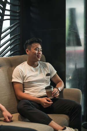 Asian young handsome man sitting in coffee shop, drinking coffee, talking and smiling.handsome young...