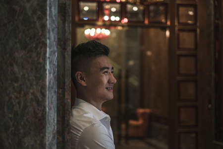 Close up portrait of asian young handsome man in white casual shirt standing outdoors and smiling. Chinese people, portraits of real peopleの写真素材