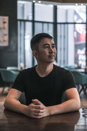 Asian young handsome man sitting in coffee shop. Chinese guy, millennials life, lifestyle in the big city, Modern Asia, coffee breakの写真素材