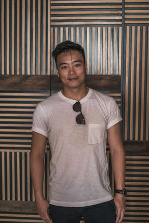 Portrait of asian young handsome man in denim shirt standing and smiling. Chinese people, real life,...