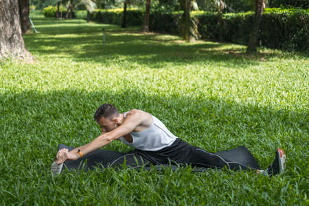Sporty active young man in sportswear doing sport exercises in the park. Portrait of handsome fit...