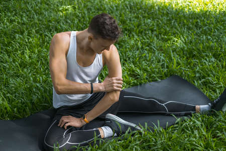 Close up portrait of man touching his arm with his hand. Man injured muscles on his arm. Sporty active young man in sportswear. Muscular fit manの写真素材