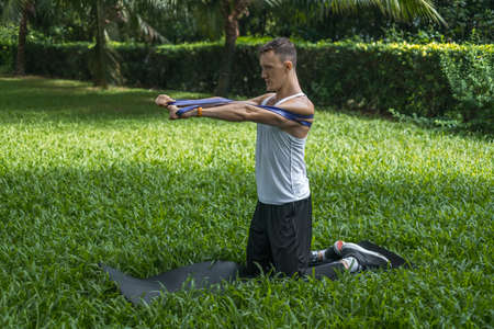 Sporty active young man in sportswear doing sport exercises in the park. Muscular fit man doing...