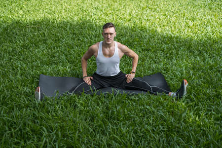 Sporty active young man in sportswear doing sport exercises in the park. Portrait of handsome fit...