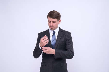 Portrait of elegant young caucasian handsome businessman in formal suit standing Isolated on white background in studio. Straightening cufflinksの写真素材