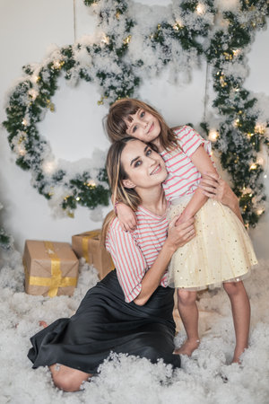 Christmas studio family shoot. New Years photo of happy family. Beautiful Mother and cute daughter are hugging each other and smilingの写真素材