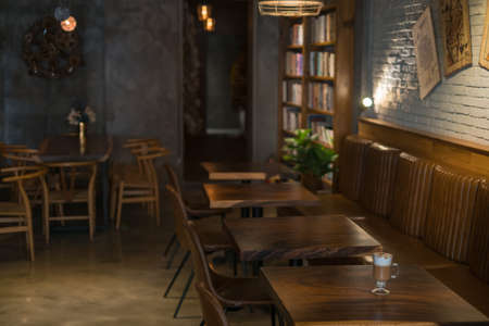 Eco cafe design in brown colours. Chandeliers made from the rope. Antique items on the wall. Solid wood furniture. Wooden shelves with books.の写真素材