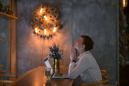 Young caucasian business man surfing the net on laptop in a bar. Handsome man working in cafe with a...