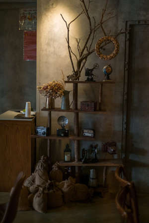 Eco cafe design in brown colours. Antique items on the wall on wooden shelves. Solid wood furniture. Dried flower bouquets. Coffee shop interior.の写真素材