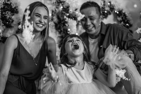 Christmas shoot. New Years photo of happy family with beautiful daughter. Man, woman and cute girl playing with artificial snow. Black and white picの写真素材