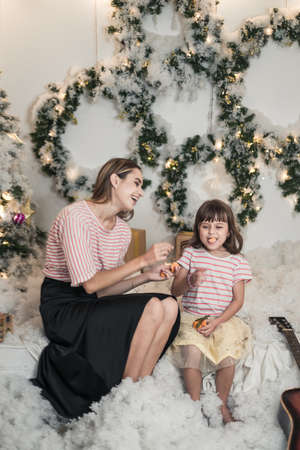 Christmas studio family shoot. New Years photo of Beautiful Mother and cute daughter have fun...