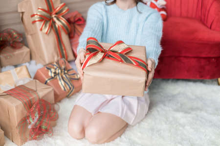 Caucasian woman in light blue sweater holding christmas gift box in in wrapping paper with bow. Christmas holiday. Copy space. High quality photoの写真素材