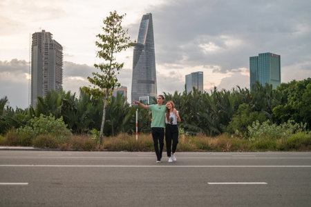 Lovely young couple walking on the street in the big city on the sunset. Boyfriend and girlfriend. Love and happiness. Skyscrapers on the backgroundの写真素材