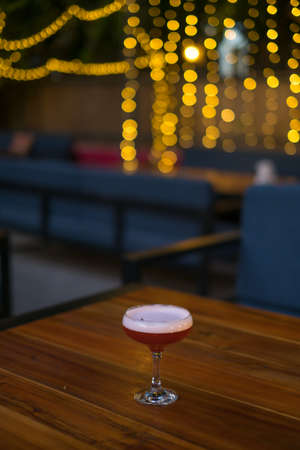 Pink tasty cocktail with foam in mister glass on the wooden table. Close up photo, bar. High quality photoの写真素材