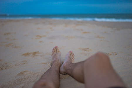Men feet on the sand at the beach, chill and relax on the beach, holidays, vacation on the beach. Male legs. high quality photoの写真素材