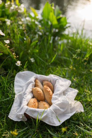 Composition of white flour buns in basket with white white cloth napkin on the green grass. High quality photoの写真素材