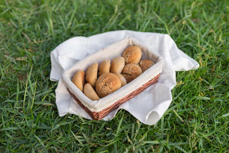 Composition of white flour buns in basket with white white cloth napkin on the green grass. High quality photoの写真素材