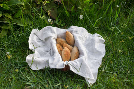 Composition of white flour buns in basket with white white cloth napkin on the green grass. High quality photoの写真素材