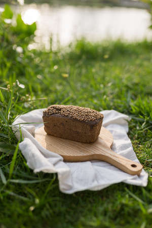 Composition of homemade custard bread on wood board with white cloth napkin on the green grass. high...