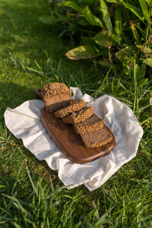 Composition of homemade custard bread on wood board with white cloth napkin on the green grass. high...