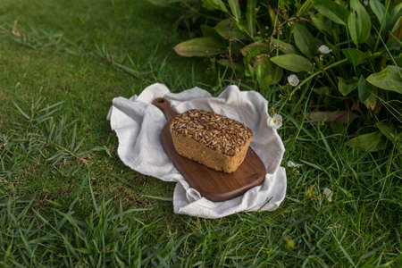 homemade grey bread with seeds on the wood board with the white cloth napkin on the green grass. High quality photoの写真素材
