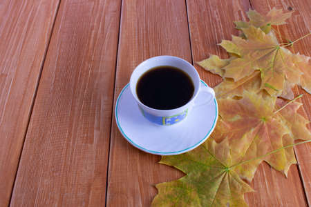 coffee Cup with autumn leaves on a brown wooden backgroundの写真素材