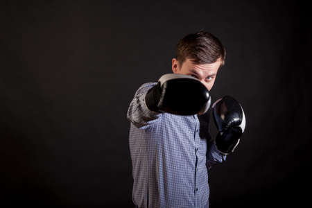 Dark-haired man in a plaid shirt with boxing gloves on his hands 
stabs on black isolated backgroundの写真素材