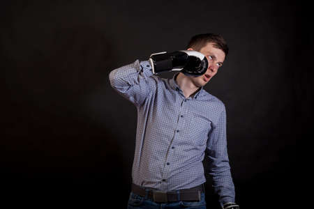 Dark-haired man in a plaid shirt with boxing gloves on his hands beats himself on black isolated...