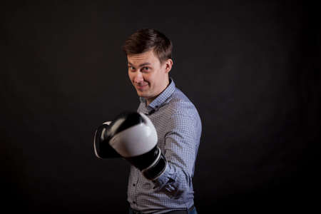 Dark-haired man in a plaid shirt with boxing gloves on his hands 
stabs on black isolated backgroundの写真素材