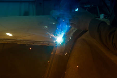 Experienced man performs work on body repair car with a welding machine. Repair of the roof of the vehicle.の写真素材