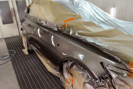 Painting the car in the workshop for body repair. Car covered with paper from hitting paint.の写真素材