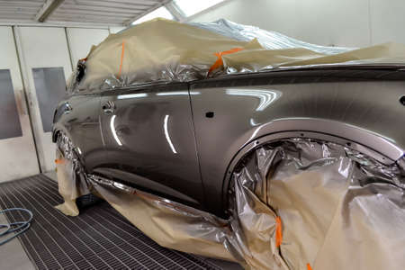 Painting the car in the workshop for body repair. Car covered with paper from hitting paint.の写真素材