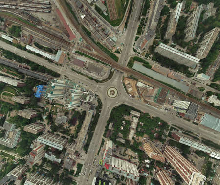 Aerial view of square in the city with roundabout traffic, streets and buildings with green trees and railway stationの写真素材