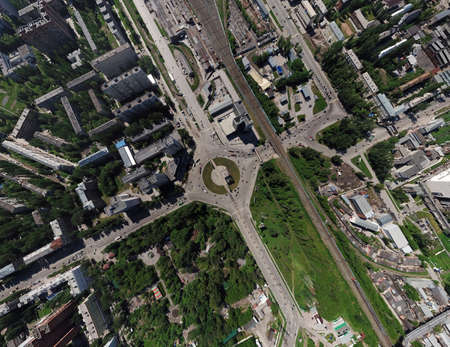 Aerial view of square in the city with roundabout traffic, streets and buildings with green trees...