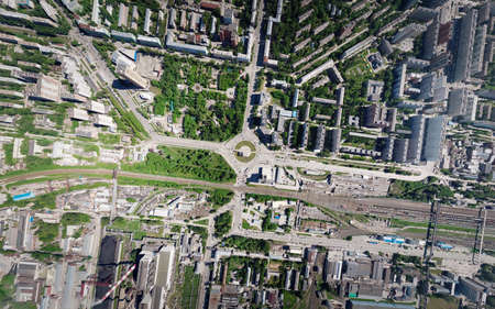 Aerial view of square in the city with roundabout traffic, streets and buildings with green trees and rails. A look from above.の写真素材