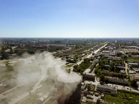 Aerial view of the red and white pipe from the plant from which the smoke is coming from the polluting air with blue skyの写真素材