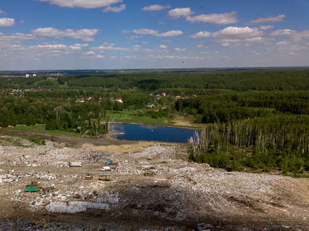 Environmental pollution. View from the air photo from flying drone of large garbage pile. Garbage pile in trash dump or landfill near the trees with small lake.の写真素材