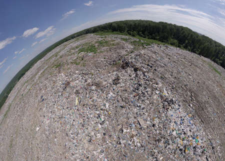 Aeral pamoramic view to a huge garbage dump located within the city, which consists of many wastes polluting the Nature and the environmentの写真素材