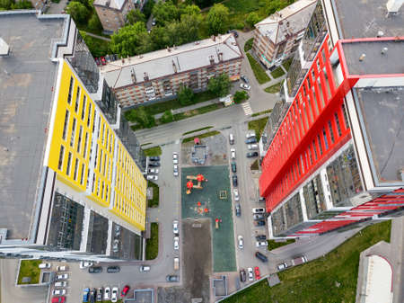Aerial view between of two tall skyscrapers of red and yellow colors among small buildings with...