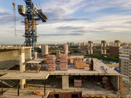 Aerial view of a new modern house under construction with a blue tower crane, red lantern at the end...