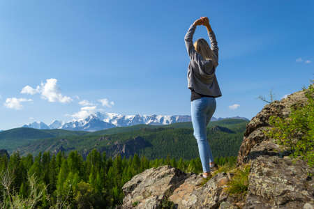 Young blonde girl stay on a rock on a sunny warm autumn summer day resting while traveling near a...