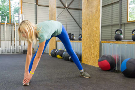 Girl in blue leggings in the gym on the background of sports equipment medical balls,dumbbells and...