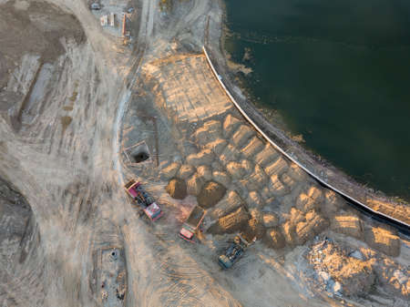 Aerial view of three multi-colored dump tip trucks unloading in a designated place at a construction...