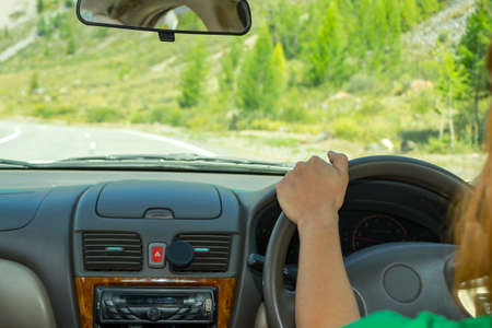 The girl drives along the asphalt road in the Altai Mountains along a serpentine road