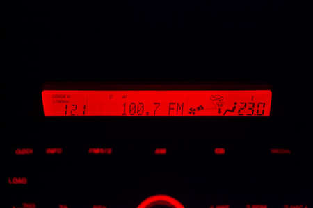 Display of the multimedia system of the car is glowing in red at night indicating the radio station,...