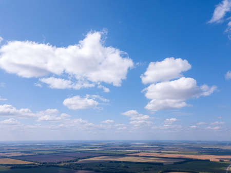 Aerial view of  landscape with agricultural fields of different color crop under a clear blue sky with clouds on a sunny warm day.の写真素材