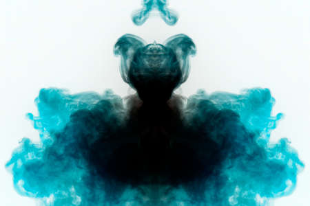Mystical pattern of multi-colored smoke in black and blue in the form of a ghost with a black body creating a feeling of fear on a white background from a horror movie.の写真素材